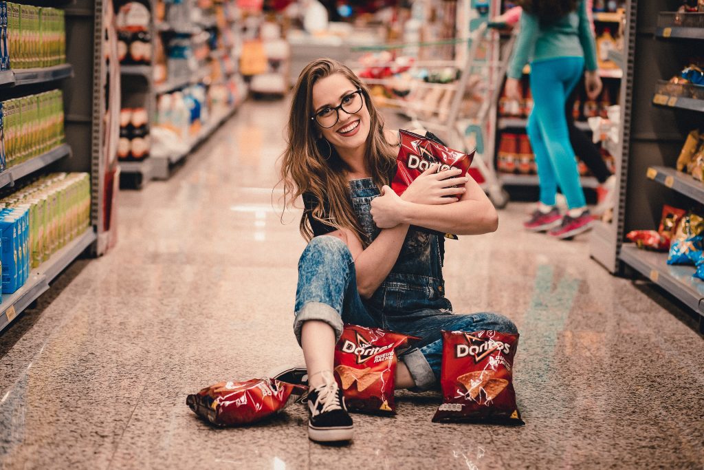 A woman sat on the floor, holding bags of Doritos